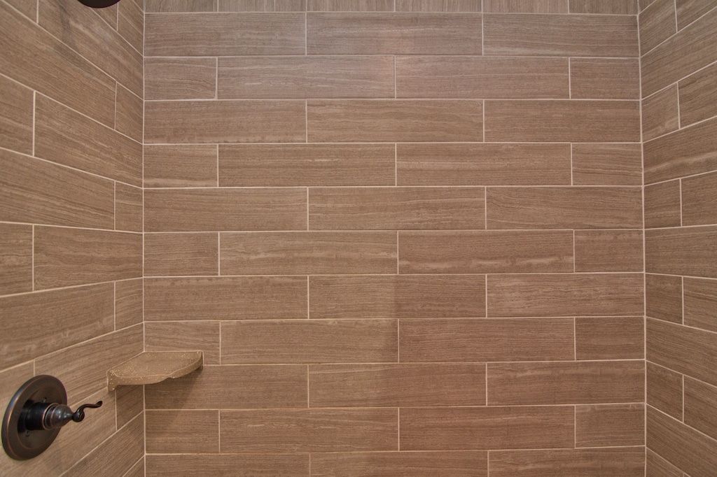 A shower with a wooden tile wall and two shower heads.