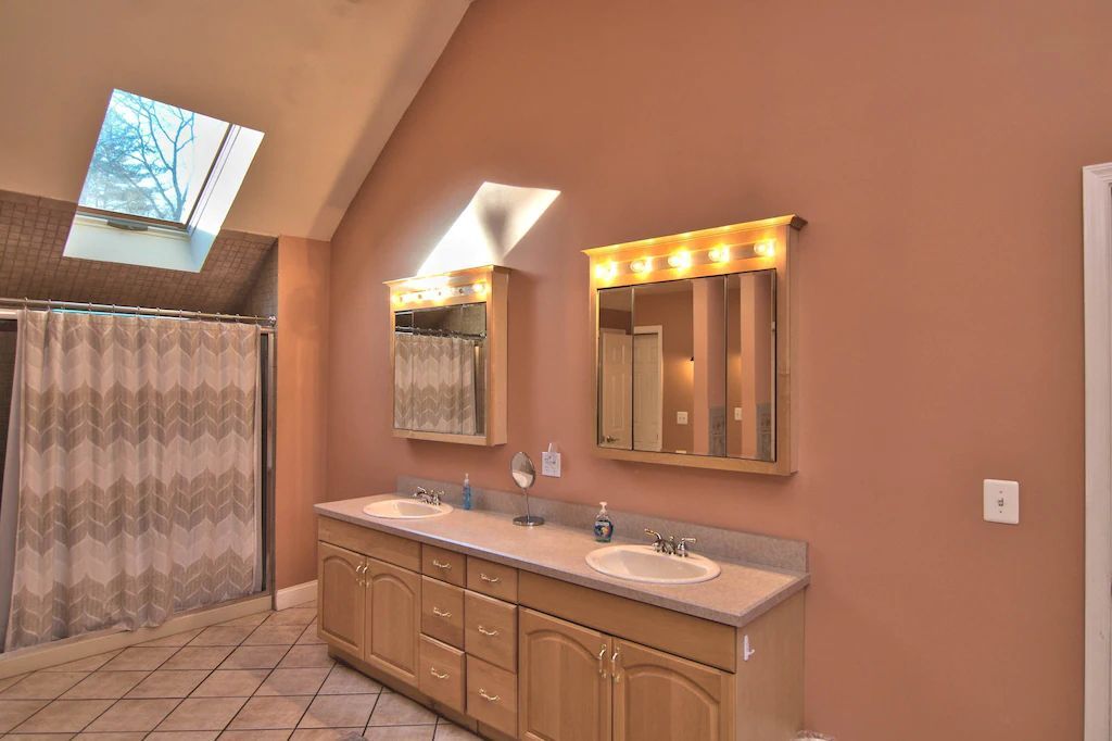 A bathroom with two sinks and a skylight