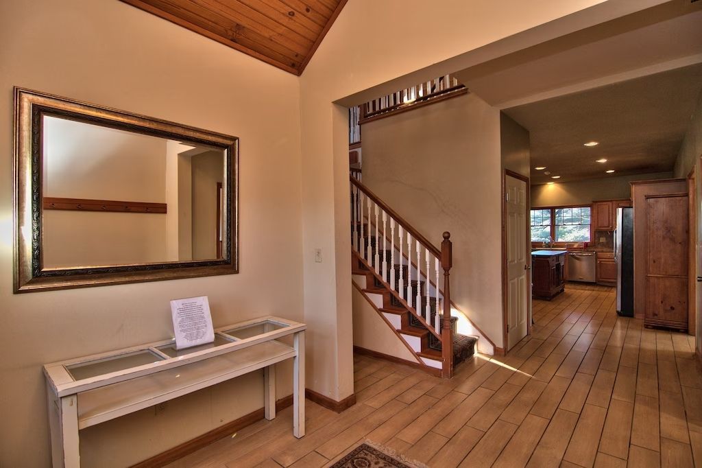 A hallway with stairs and a mirror on the wall