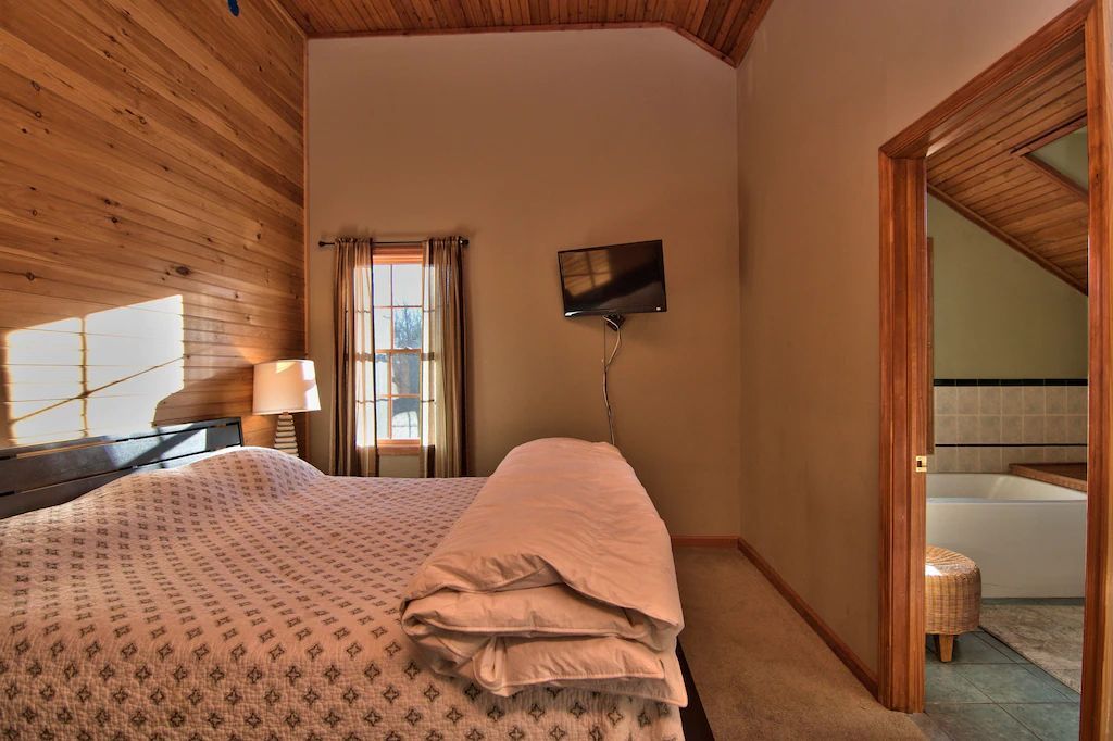 A bedroom with a king size bed and a television on the wall.