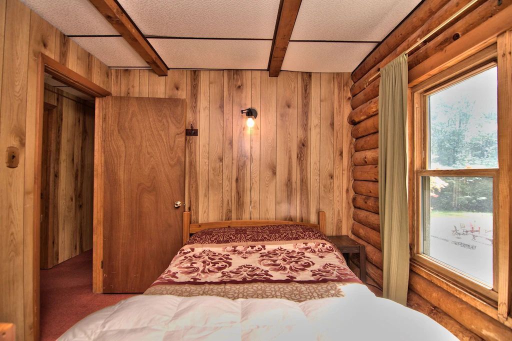 A bedroom in a log cabin with a bed and a window
