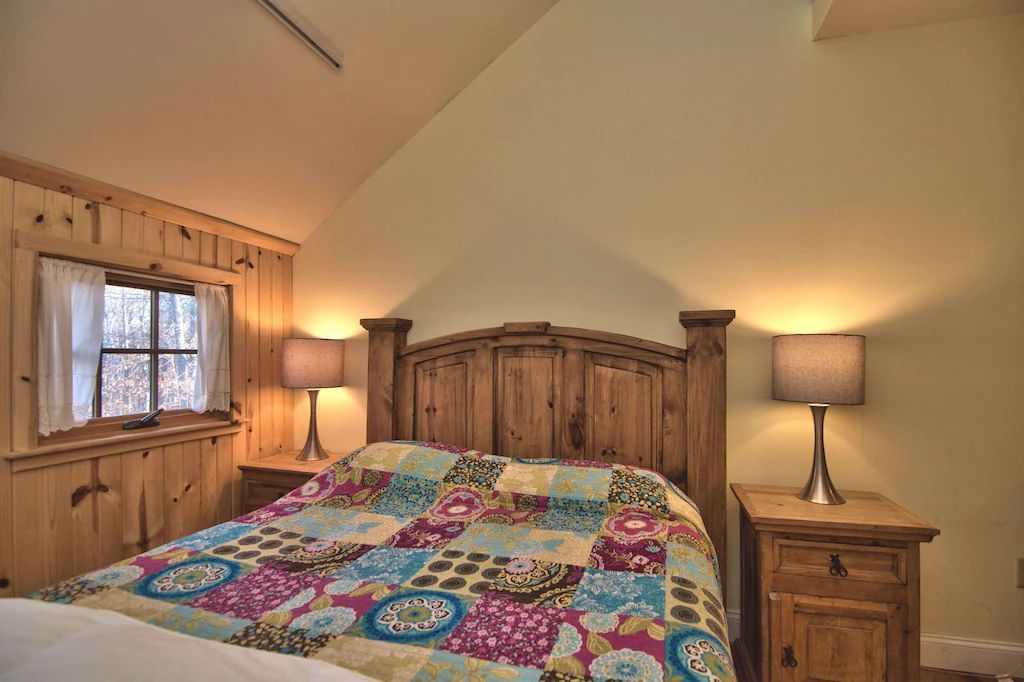 A bedroom with a bed , nightstands , lamps and a window.
