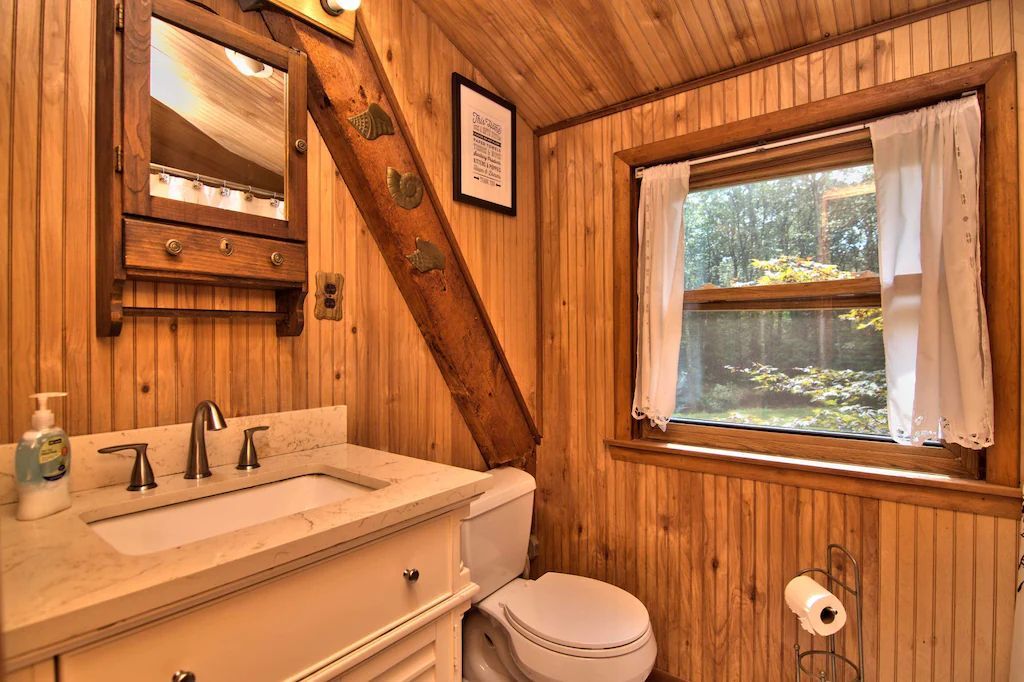 A bathroom with a sink , toilet , mirror and window.