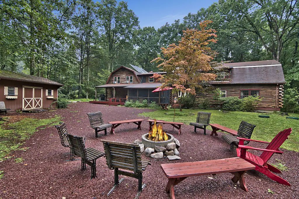 A fire pit surrounded by chairs and benches in front of a house.