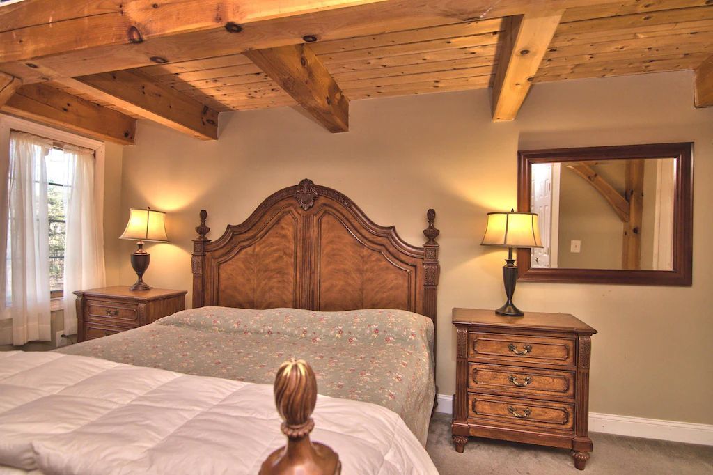 A bedroom with a large bed , nightstands , lamps and a mirror.