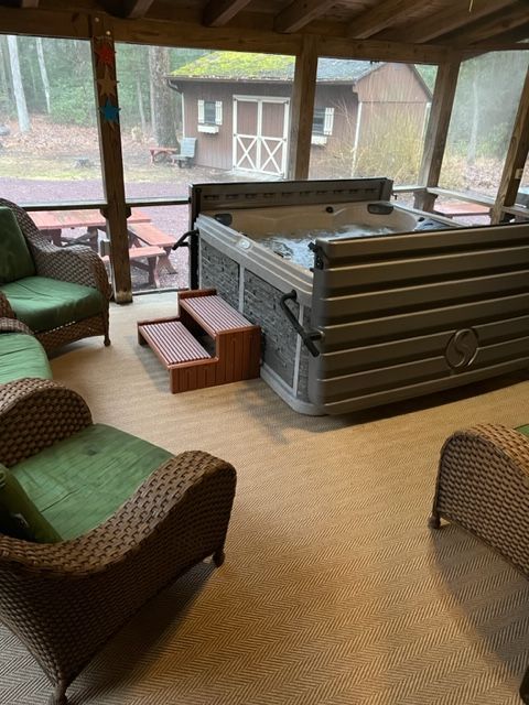 A screened in porch with a hot tub and chairs