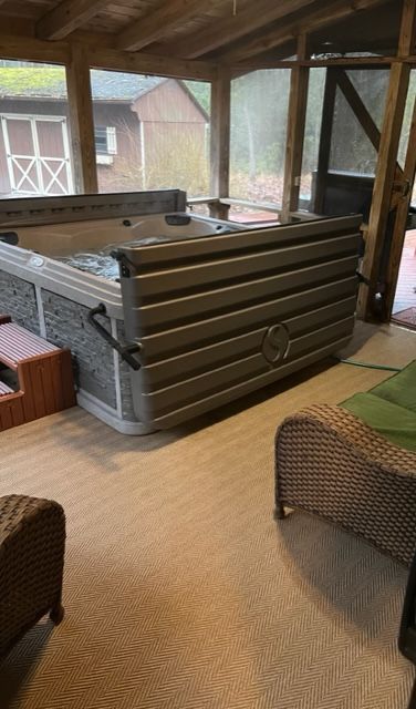 A large hot tub is sitting inside of a screened in porch.