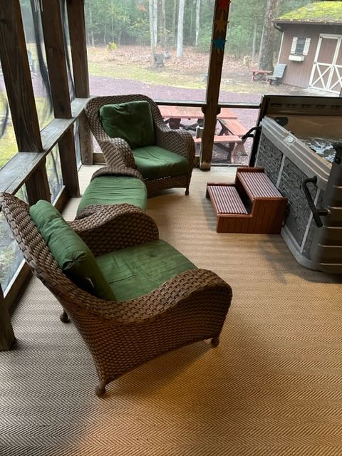 A screened in porch with wicker furniture and a hot tub