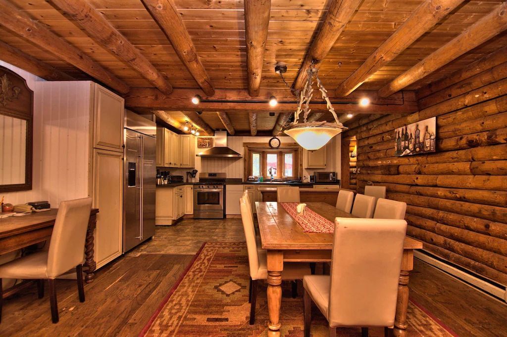 A dining room in a log cabin with a long table and chairs.