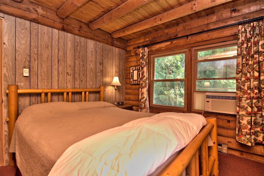 A bedroom in a log cabin with two beds and a window.