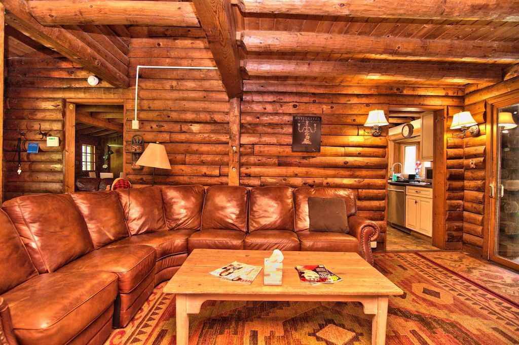 A living room in a log cabin with a couch and a coffee table.