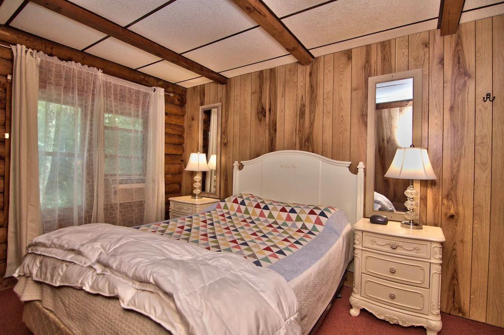 A bedroom with a bed , nightstand , mirror and lamps.