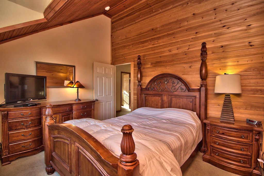 A bedroom with a king size bed , dresser , nightstand , lamp and television.
