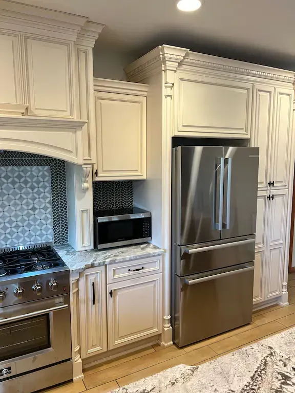 A kitchen with stainless steel appliances and white cabinets.
