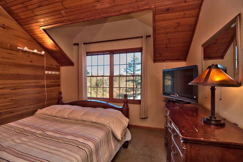 A bedroom with a bed , dresser , lamp and television.