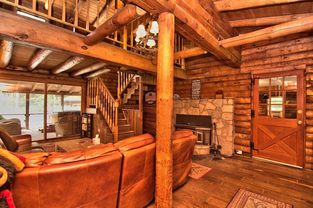 A living room in a log cabin with a couch and a fireplace.