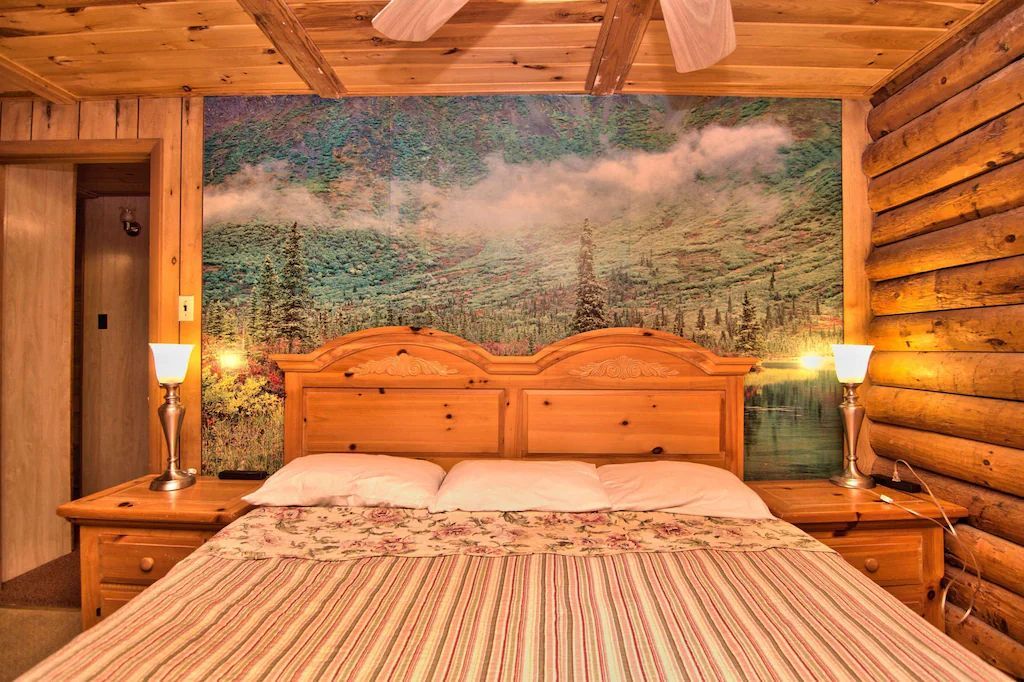 A bedroom in a log cabin with a large bed and a painting on the wall.