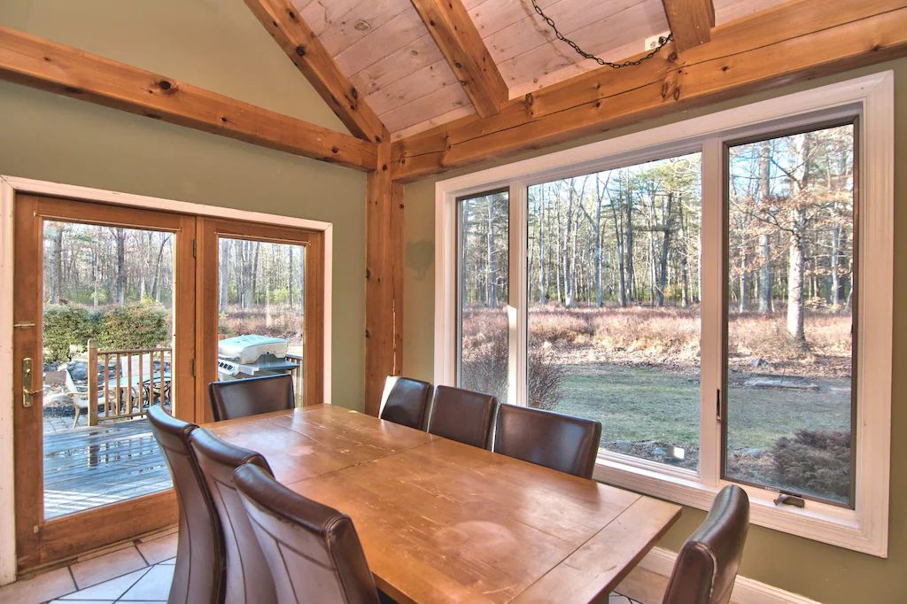 A dining room with a table and chairs and lots of windows