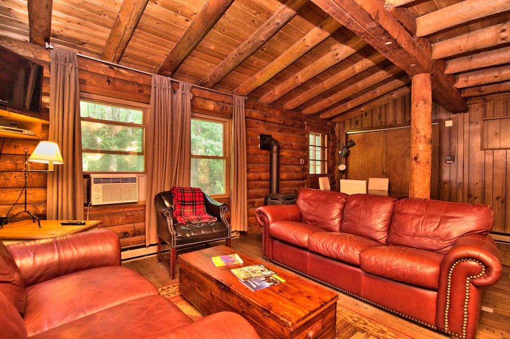 A living room in a log cabin with a couch , chairs , and a coffee table.