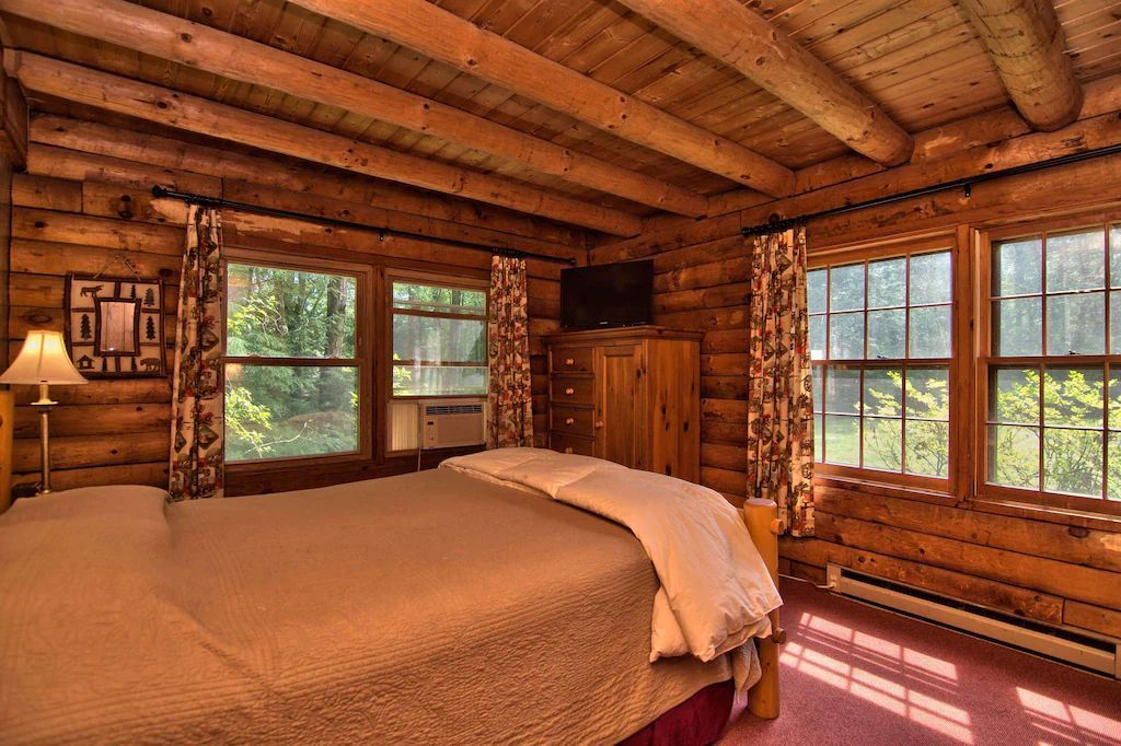 A bedroom in a log cabin with a large bed and lots of windows.