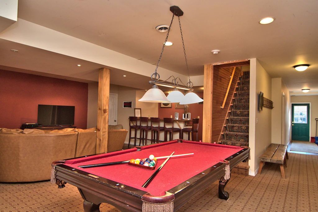 A pool table in a basement with a staircase in the background
