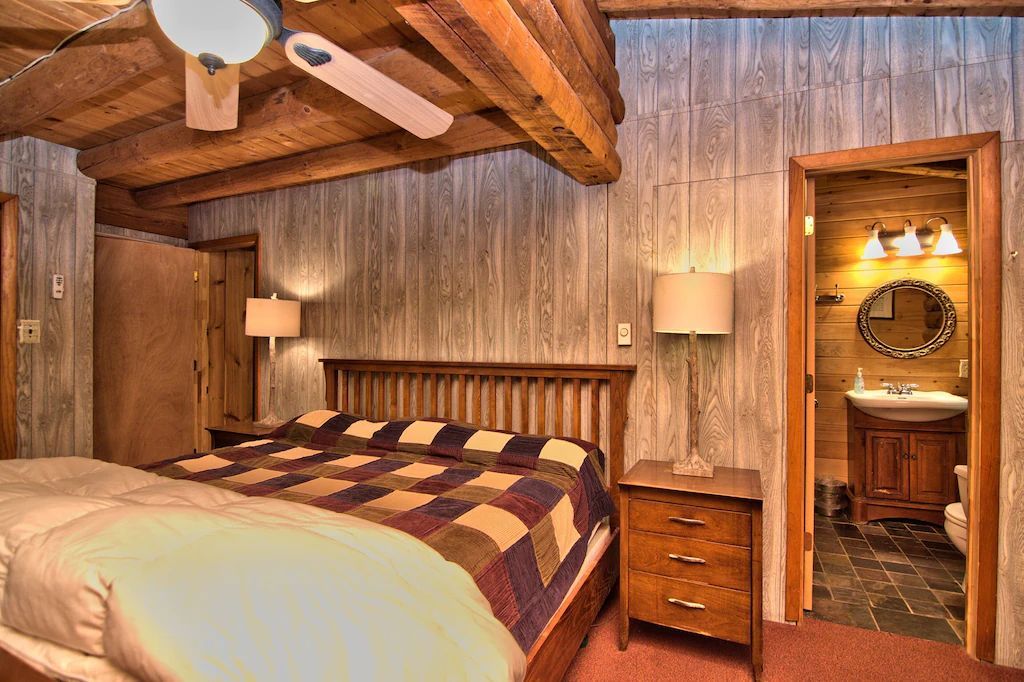 A bedroom in a log cabin with a king size bed and a bathroom.