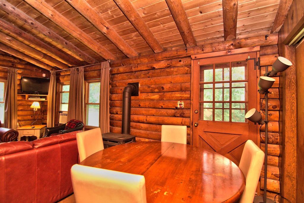 A log cabin with a dining table and chairs in the middle of the room.