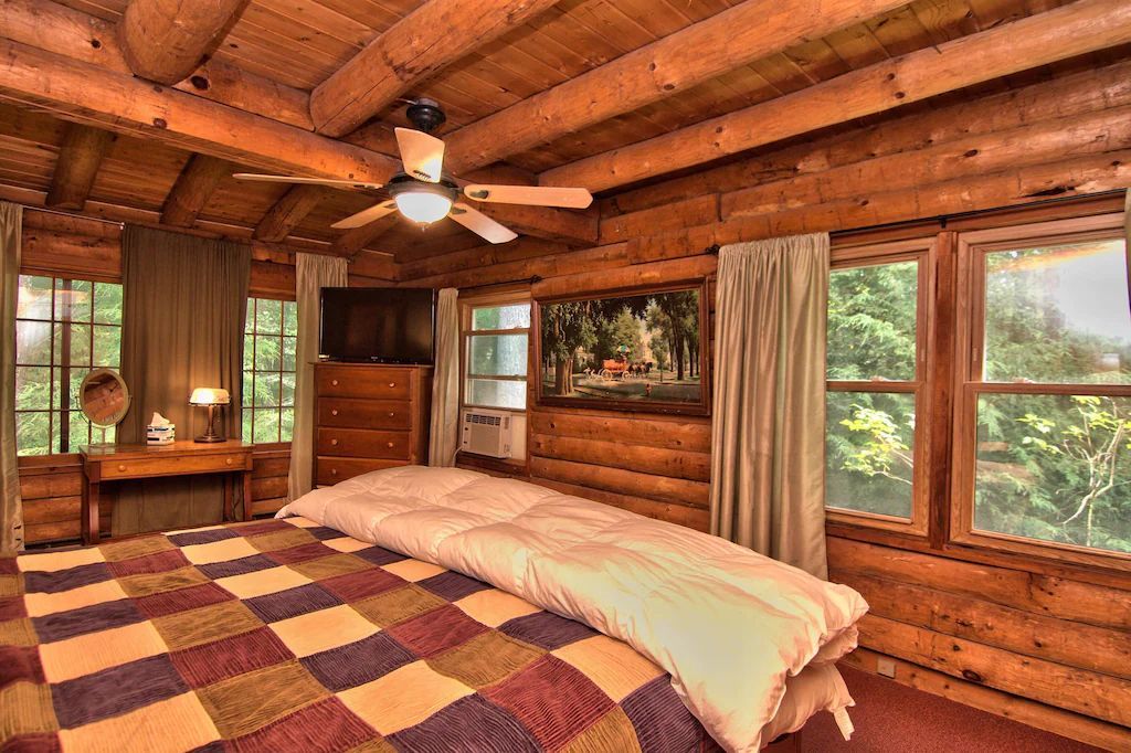 A bedroom in a log cabin with a king size bed and a ceiling fan.