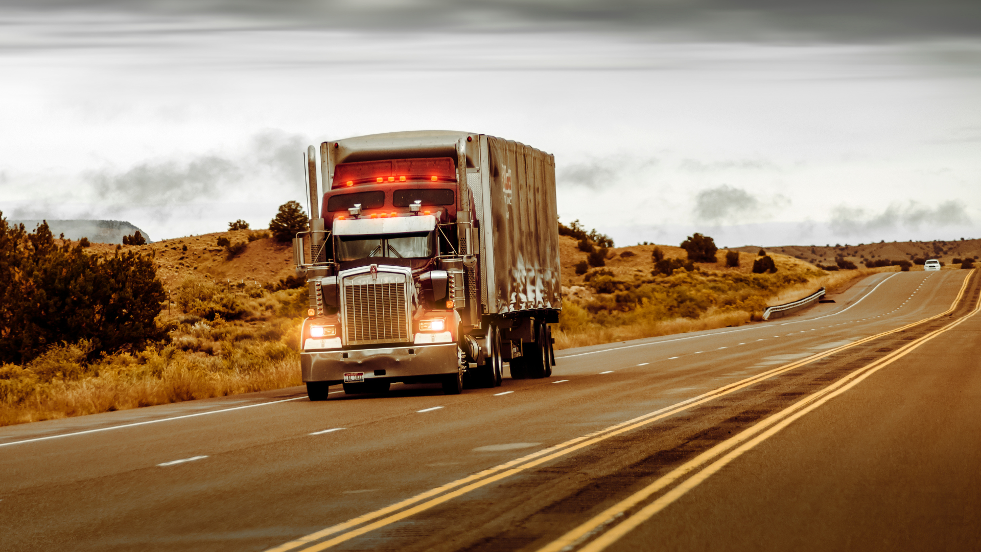 a semi truck is driving down a highway in the desert .