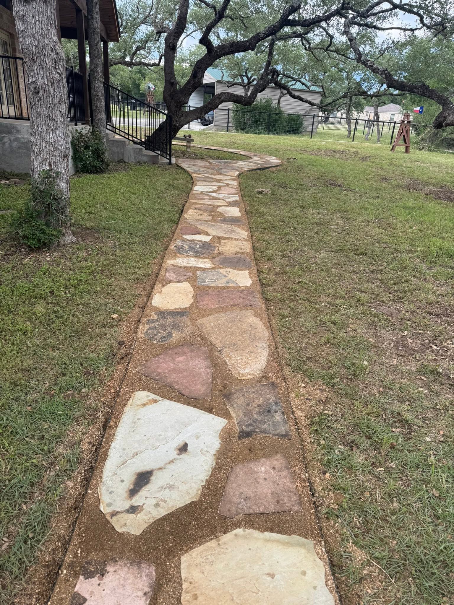 Stone path through grassy park with trees on both sides