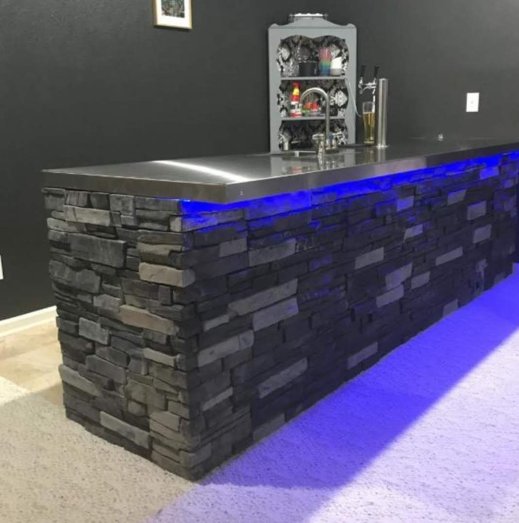Stone bar with stainless steel top and blue underlighting. A small bar fixture sits atop the bar.