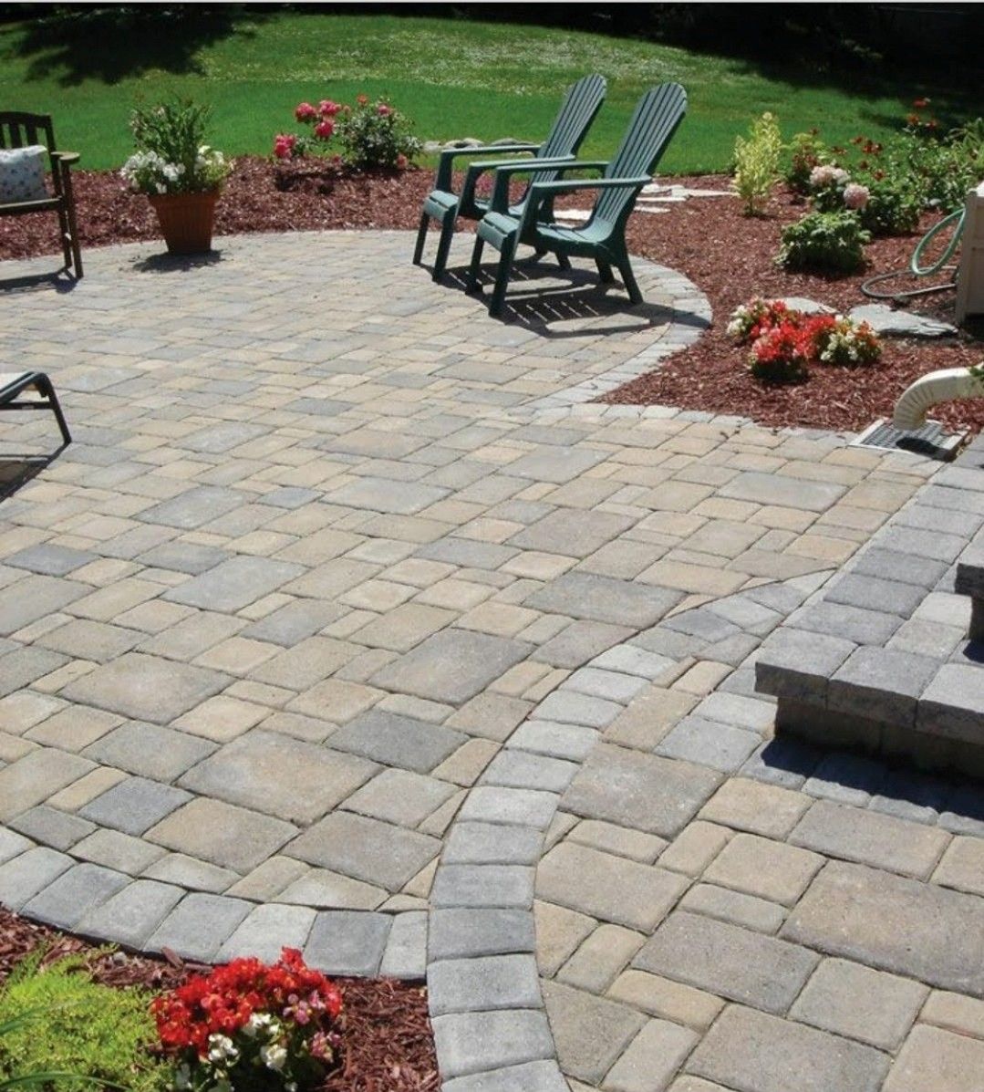 Patio with patterned pavers, green chairs, and red mulch landscaping.