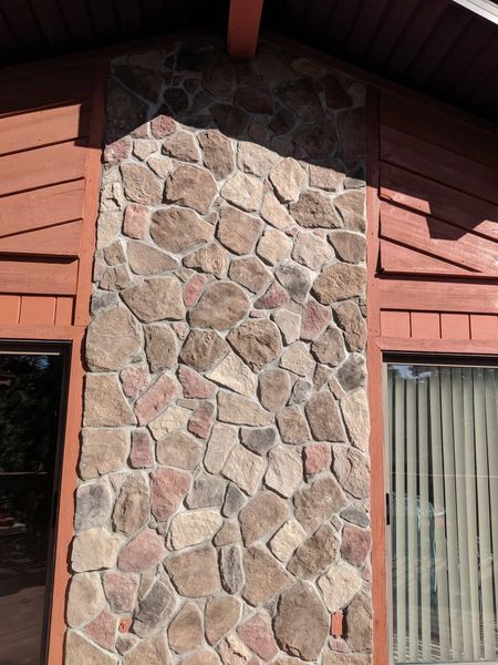 Stone facade on a building between red siding.