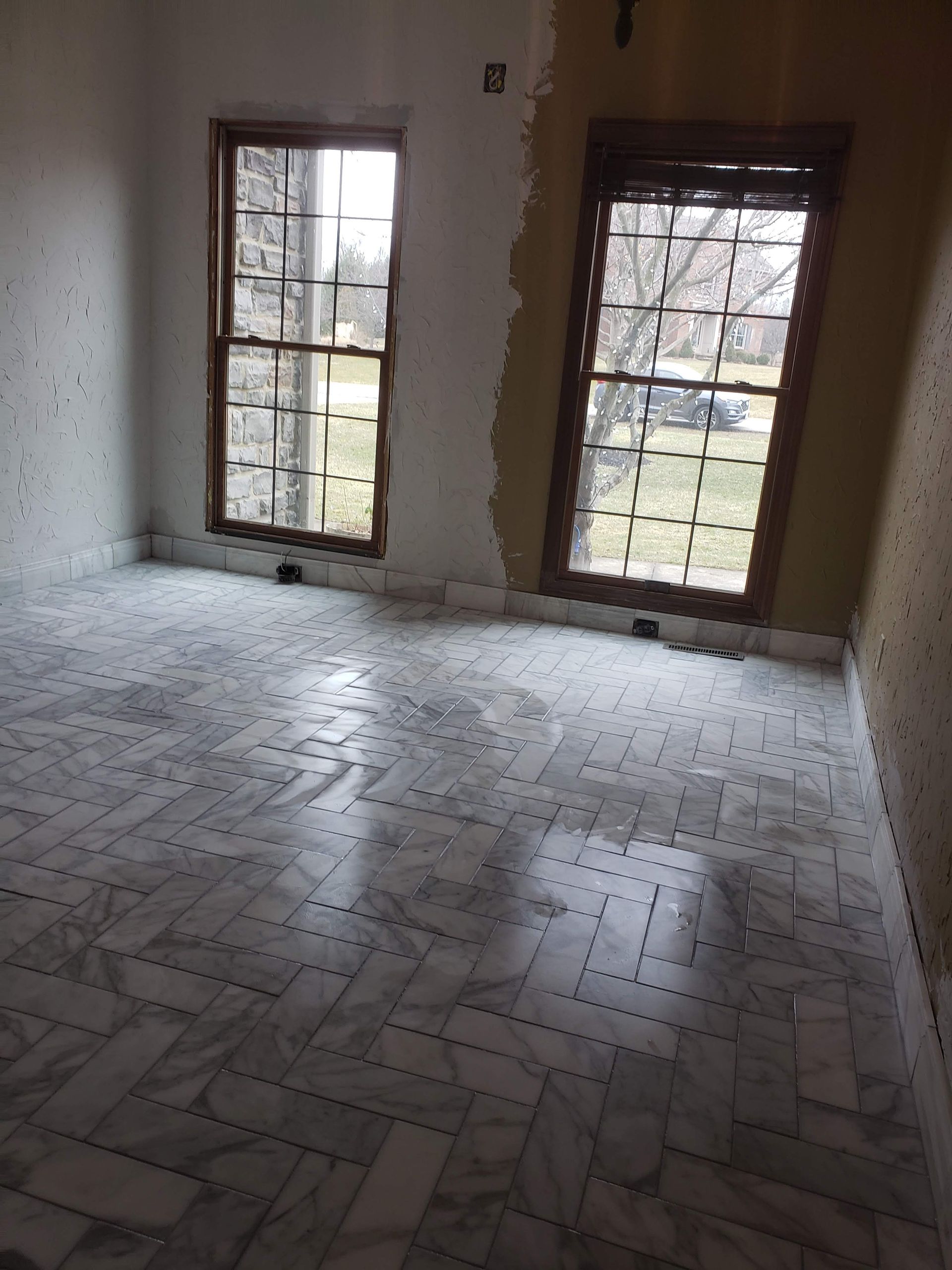 Room with marble tile floor and two windows with wooden frames.