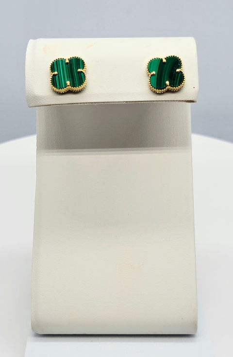 White display stand with green and gold stud earrings at the top