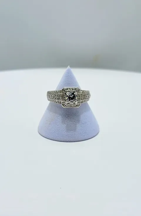 Silver ring with a dark center stone displayed on a lavender cone stand.