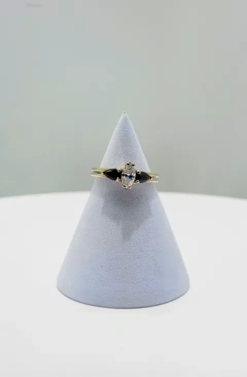 Gold and black ring on a small white cone display against a plain gray background