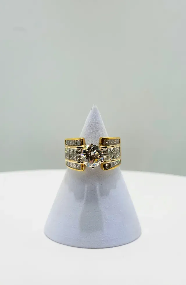 Gold and black ring with geometric design displayed on a gray cone stand.