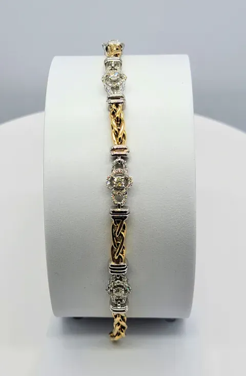 Gold and silver bracelet with ornate links displayed on a white jewelry stand