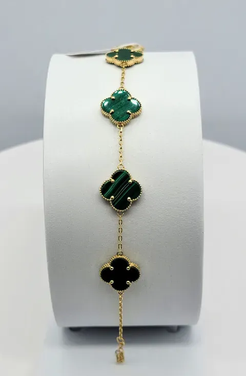 Gold bracelet with four green clover-shaped charms on a white display stand