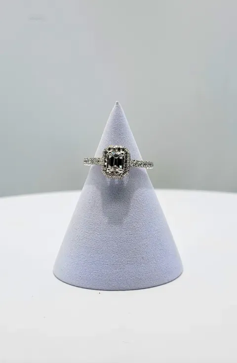 Silver ring with a rectangular black gemstone on a lavender cone display stand.