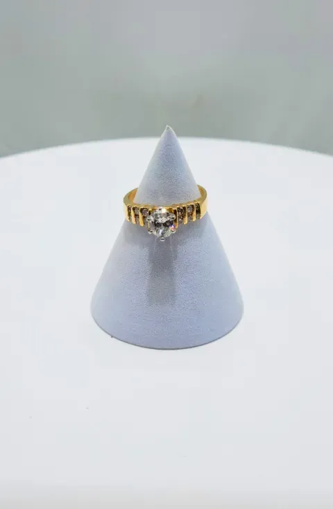 Gold ring on a gray cone display stand against a white surface.