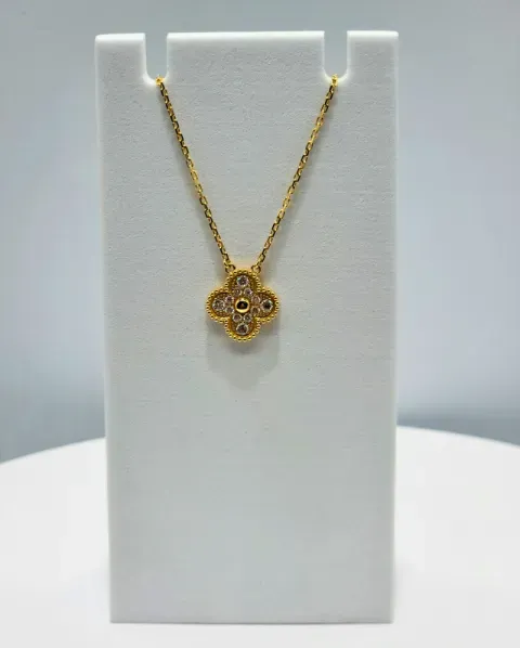 Gold flower pendant necklace on a white display stand