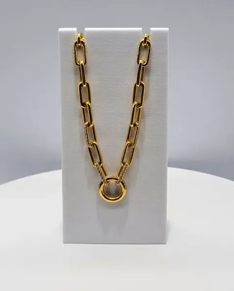 Gold chain necklace with a round pendant displayed on a white stand.
