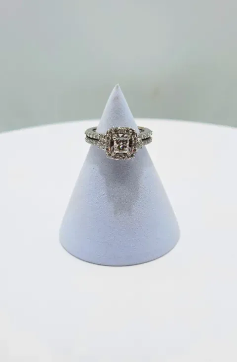 Silver ring with a large gemstone displayed on a light blue cone stand
