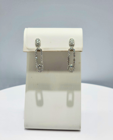 Pair of silver drop earrings displayed on a white jewelry stand