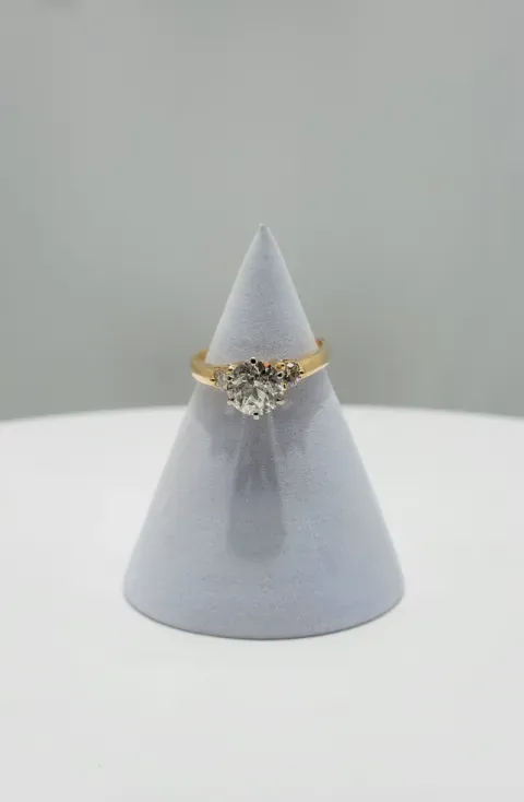 Gray cone-shaped jewelry display with a gold ring and clear gemstone on top
