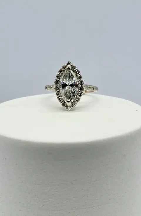 Silver oval gemstone ring on a white display pedestal against a gray background