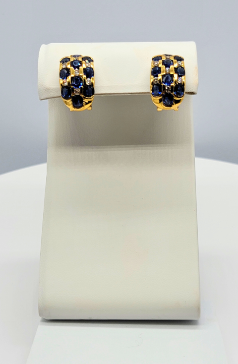 Gold hoop earrings with blue and black stones on a display stand