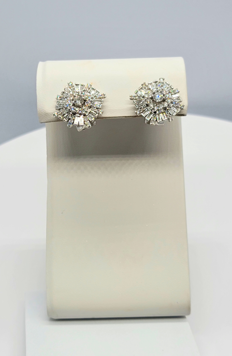 Pair of silver floral stud earrings displayed on a white jewelry stand.